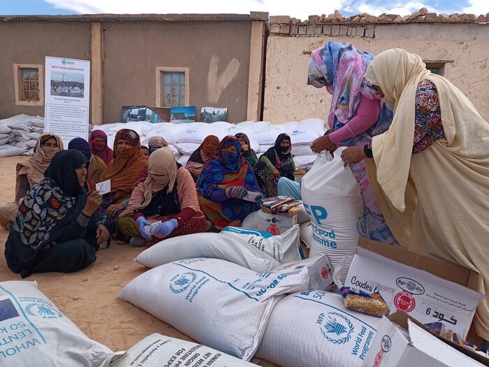 Sahrawi refugee women sit in groups to distribute the monthly food rations, always protecting their heads and faces from the harsh desert sun.
