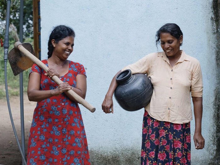 Two women carrying their equipment to work in their field