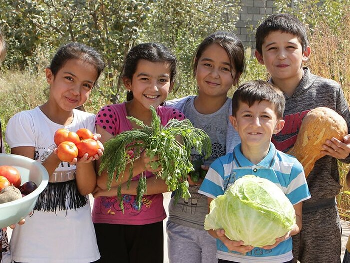 Group of children holding freshly harvested vegetables