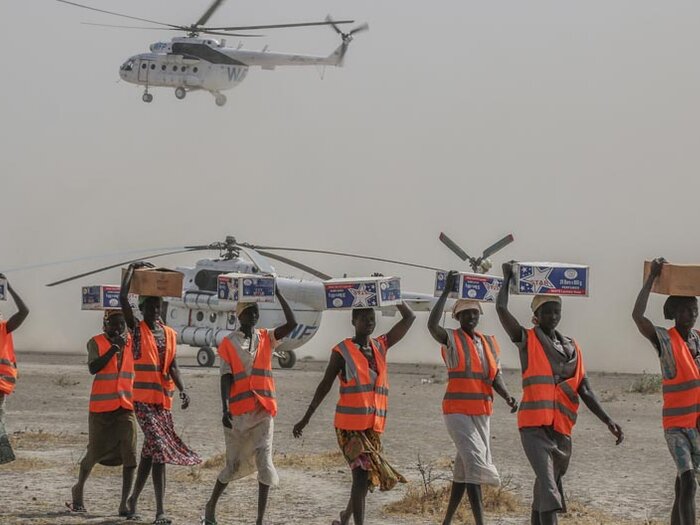 Women wearing vests offloading relief supplies from UN Humanitarian Air Service helicopters