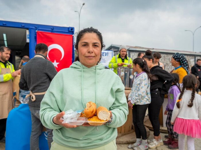 Neşe (37y) queueing at the WFP hot meals distribution point at a shelter camp next to the Hatay/Antakya Expo Fairground complex.