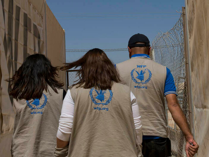 Three WFP staff walking up an alley