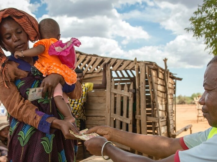 Woman holding her baby and receiving cash assistance