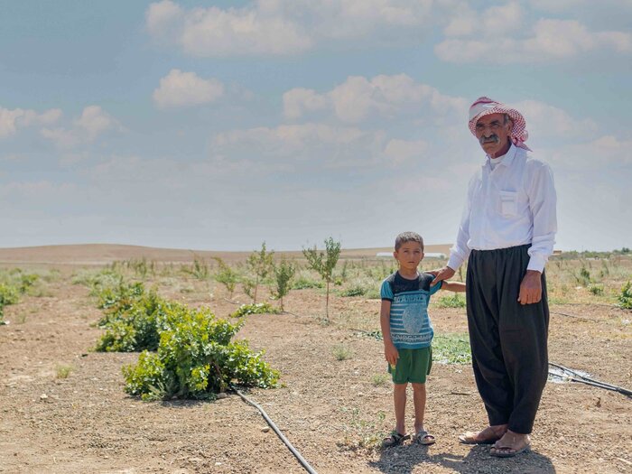 Mukhtar from Sinjar in Ninawa governorate with his son at the orchard under rehabilitation with WFP's support.