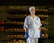 A woman in bakers' whites stands in front of rows of baked bread