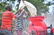 Farmers pour maize from a burlap bag into a red threshing machine. Photo: WFP/Michael Tewelde