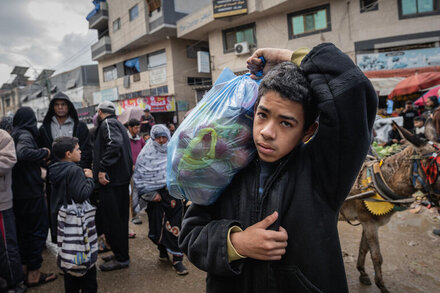 boy carrying a bag of food in his shoulder