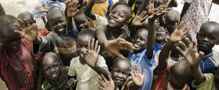 group of kids smiling at waving at the camera in South Sudan
