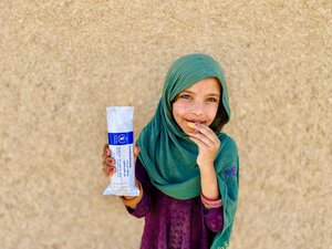 A smiling Afghan primary schoolgirl displays a package of WFP fortified biscuits. Photo: WFP/Sayed Abidullah Sadat