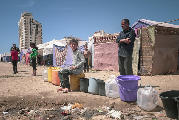 Photo: WFP/Photo library. displaced Palestinians line up and wait to fill their containers with water in Gaza City