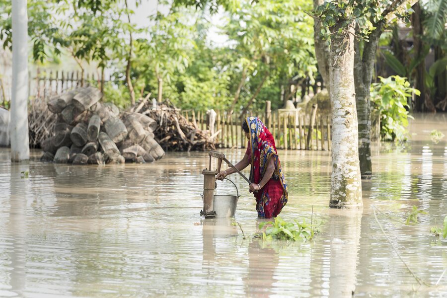 A woman fetching water from a pump after severe flooding