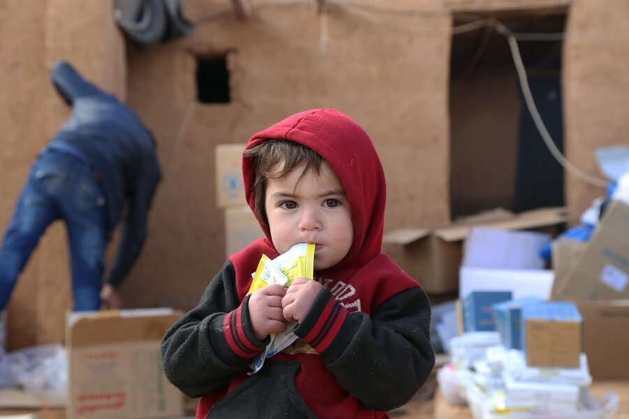 A child eating from a food packet at a settlement in Syria