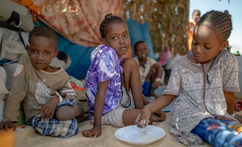 two girls and a boy eating from a plate in Sudan