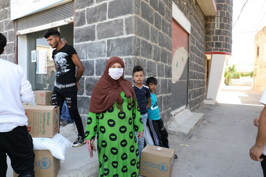 Um Ali collects food for her family in her new home in Southern Damascus. Photo: WFP/Hussam Alsaleh.
