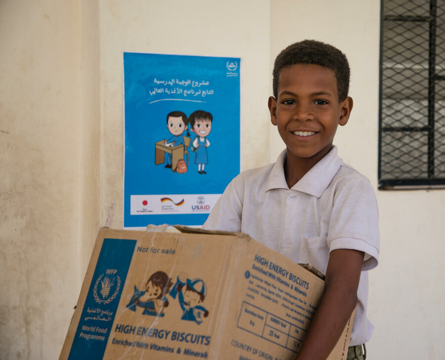 A boy takes delivery of a box of high-energy biscuits at a school in Yemen