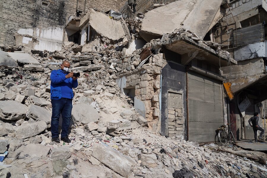 Hussam Al-Saleh standing over the rubble in Aleppo while taking a photo ten years after conflict changes the face of the city.