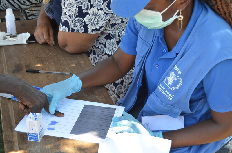 WFP beneficiary signing the registration list to receive the food package, it is being  signed with finger prints..