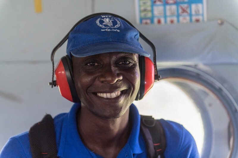 WFP frontline worker, on a helicopter smiling. He is helping deliver food to those affected by Cyclone Idai, Mozambique