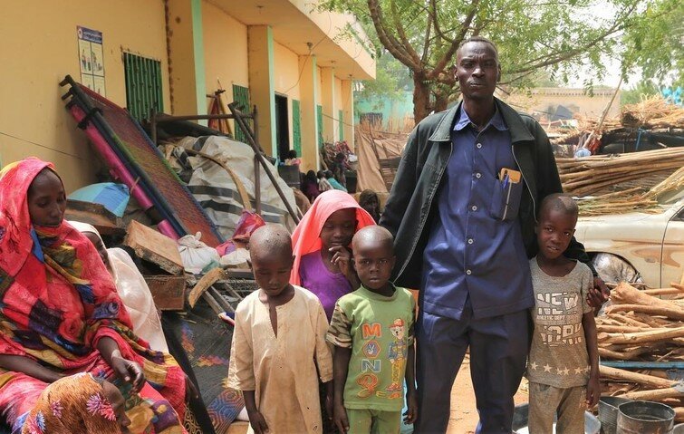 Yahya (R) poses for a picture with his family at their makeshift home at the State Ministry of Welfare in Geneina.