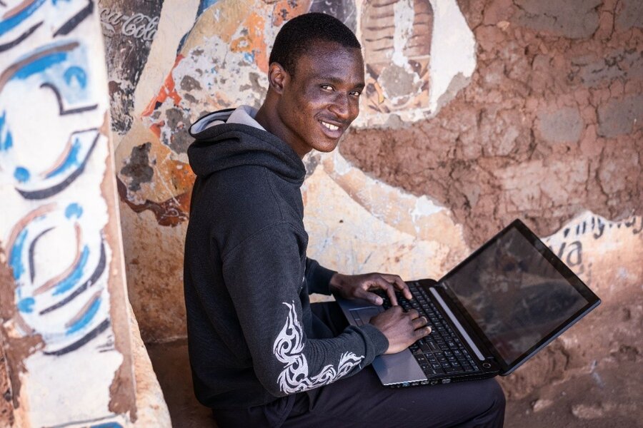 A man works on his laptop which sits on his lap.