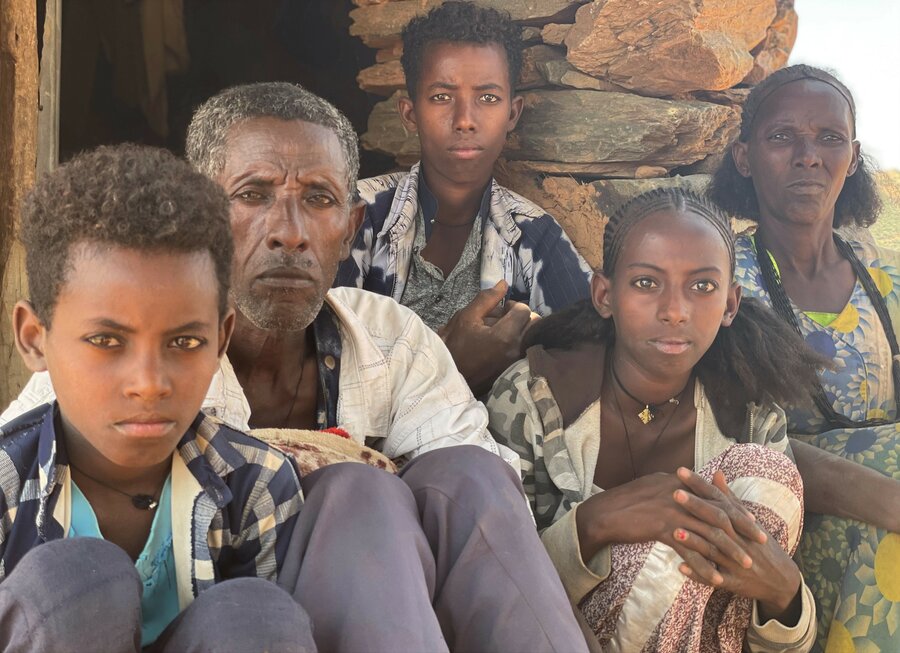Aster and her husband Tesfay and three of their children sit together outside a one-roomed shelter where they are living temporarily since their home was set ablaze. Photo: WFP/Claire Nevill