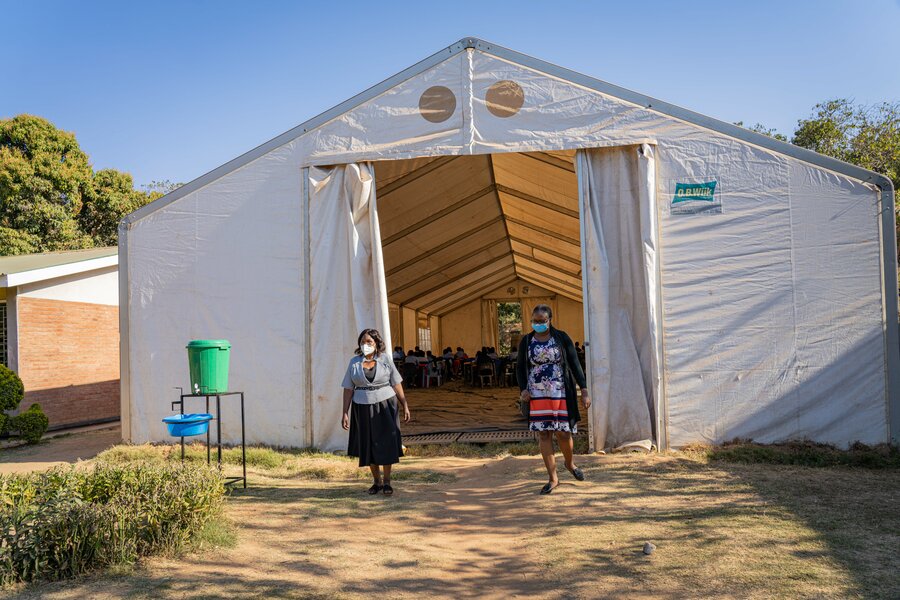 Two women walking out of the spacious tent.
