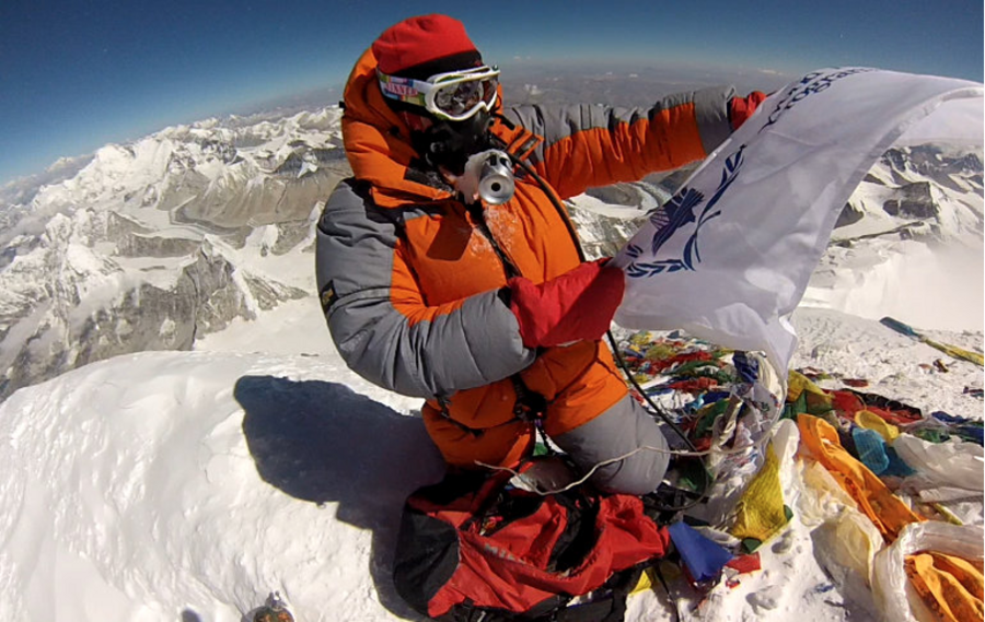 Woman planting flag at top of mountain