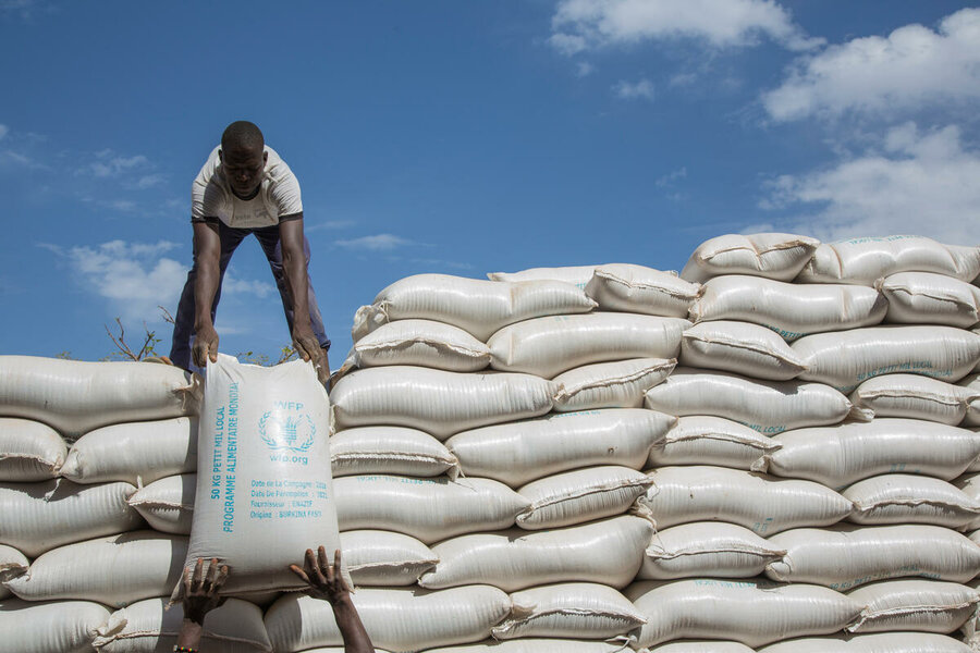 man offloading sacks of food against blue sky background