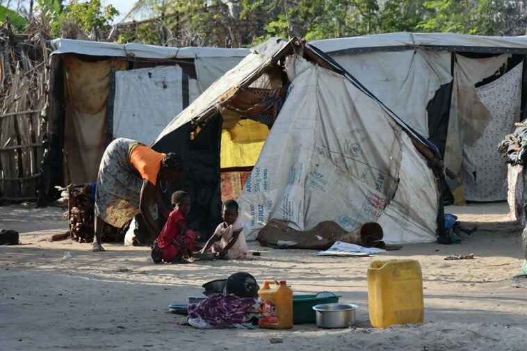 Children sit outside a tent.