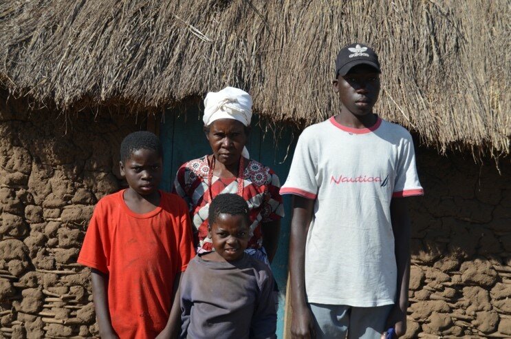 A family of four pose outside of their home.