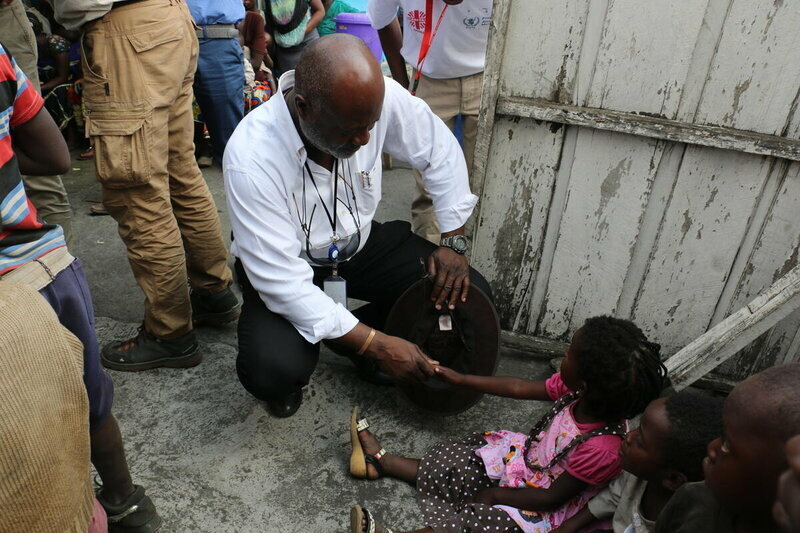 man kneels to speak to child