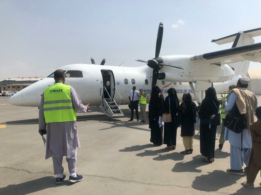 people queue on tarmac to get on UNHAS flight