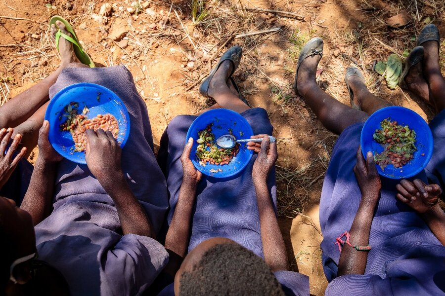 An overhead shot of three girls eating from blue bowls.