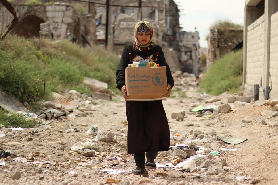 A woman carries supplies from a WFP distribution in Aleppo, Syria. WFP/Khudr Alissa