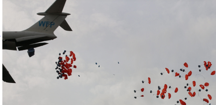 orange parachutes drop out of wfp plane against cloudy sky