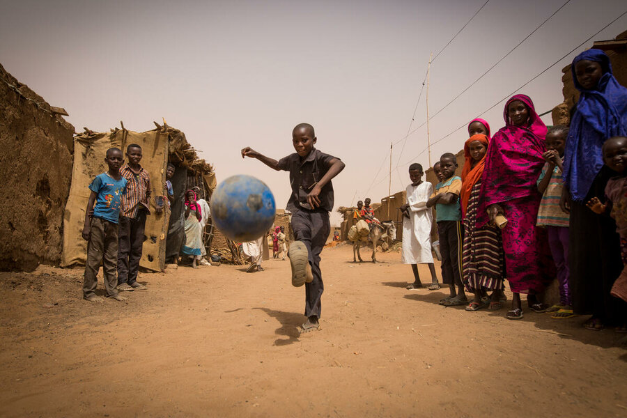 a boy is playing football in the street