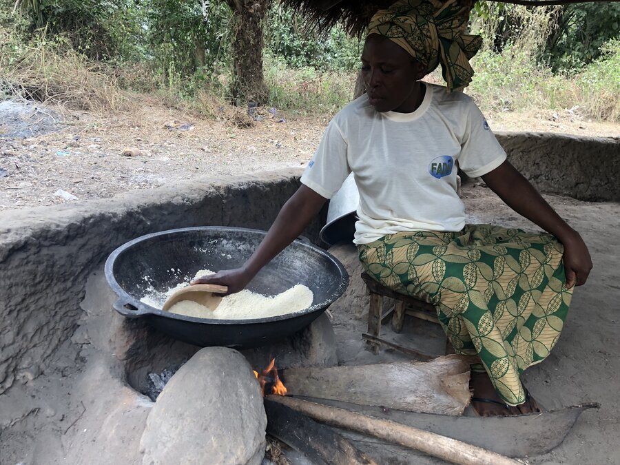 Benedicte Kindjinon pan-fries her gari under a thatched roof kitchen in her backyard. Photo: WFP/Djaounsede Madjiangar