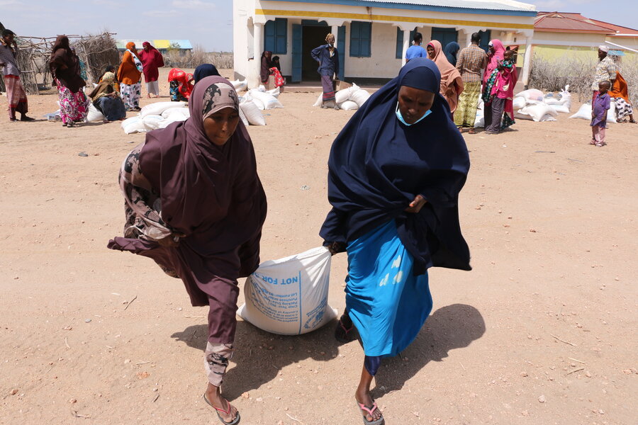 Two women carrying a sack of food