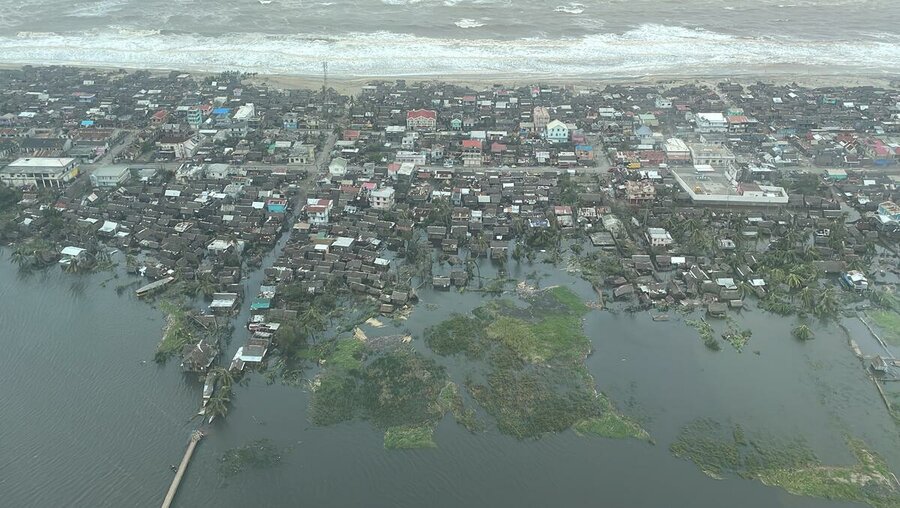 aerial view of coastal town hit by cyclone with houses trapped between ocean and flood waters