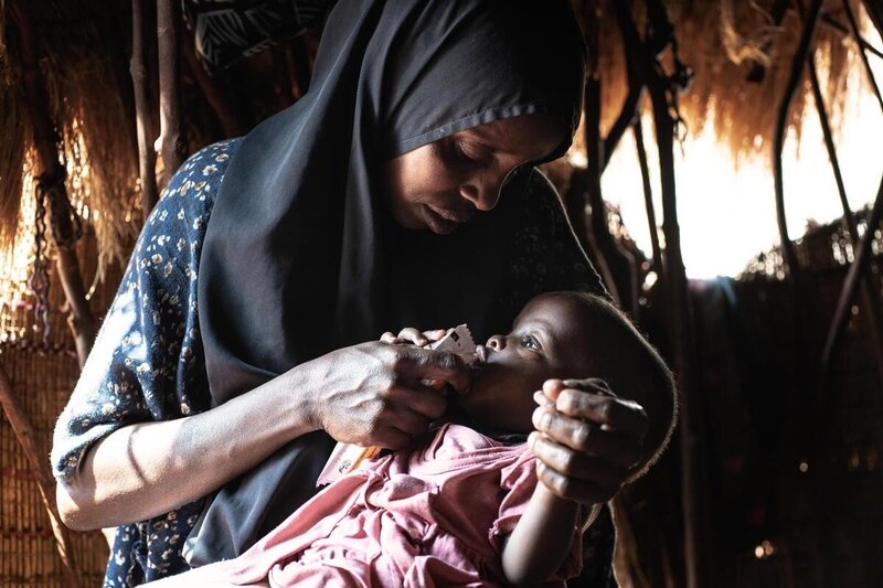 Mahadha feeds her bay daughter a peanut paste supplied by WFP