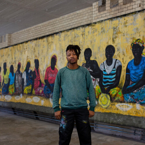 Ryan is standing in front of a wall that covered with graffiti