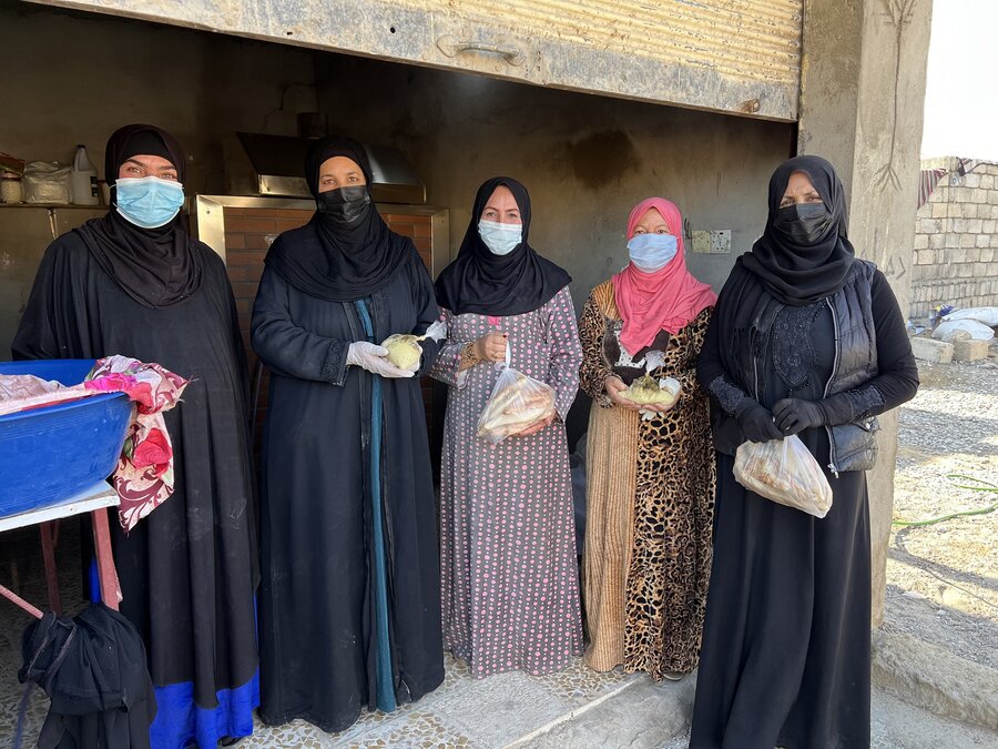 Five Iraqi women stand in a line out the front of a bakery where they work.