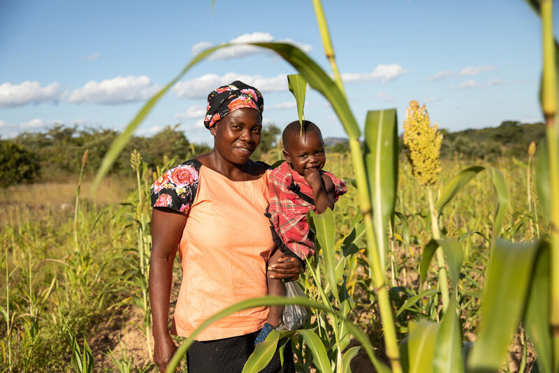 A mother holds a child in a field