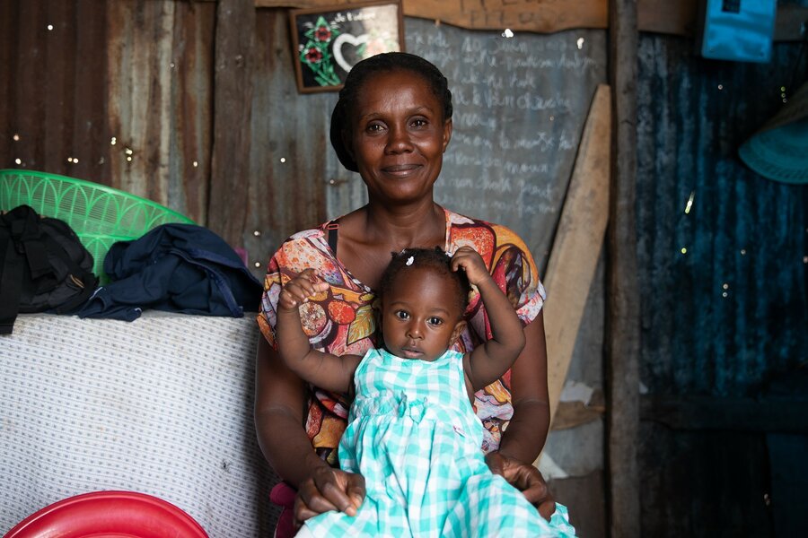 A mother holds a baby girl who is holding her arms up