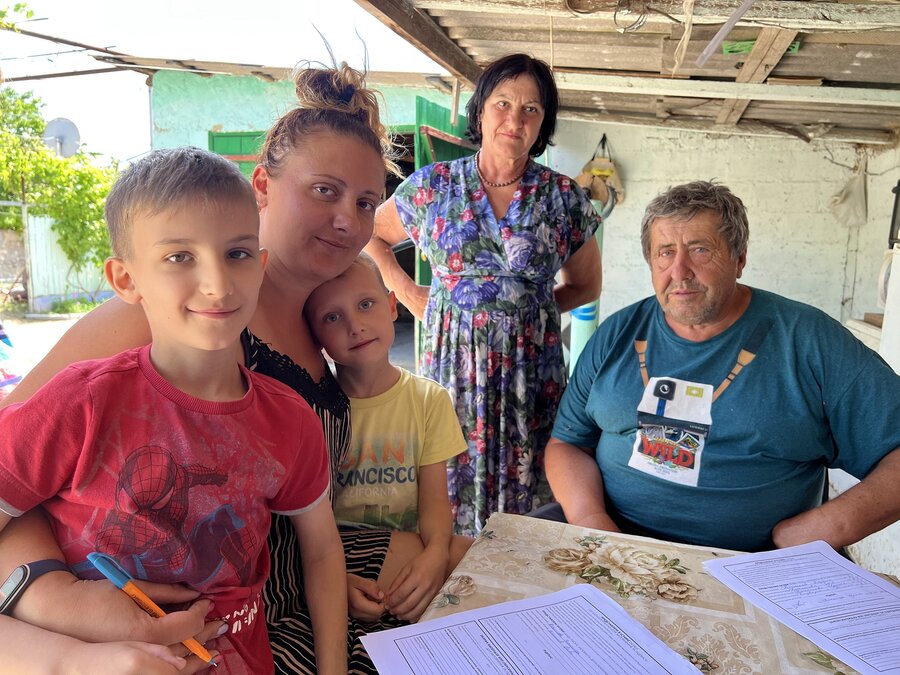 A family of 2 grandparents, 1 mother and 2 sons gather around a table