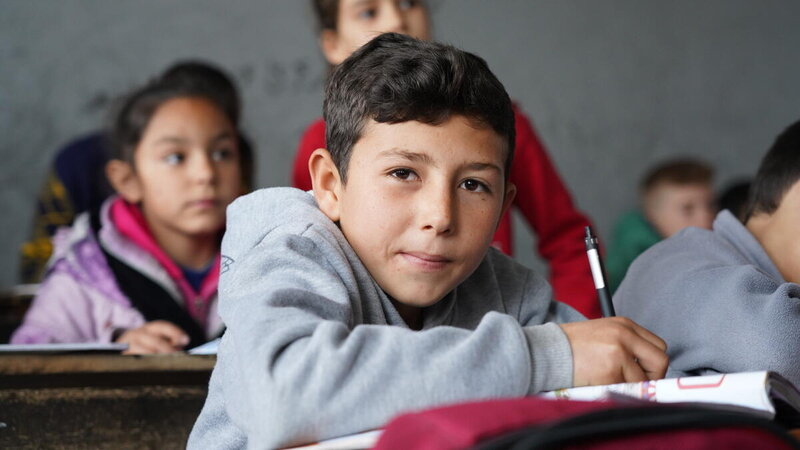 a boy is sitting on a desk at his school