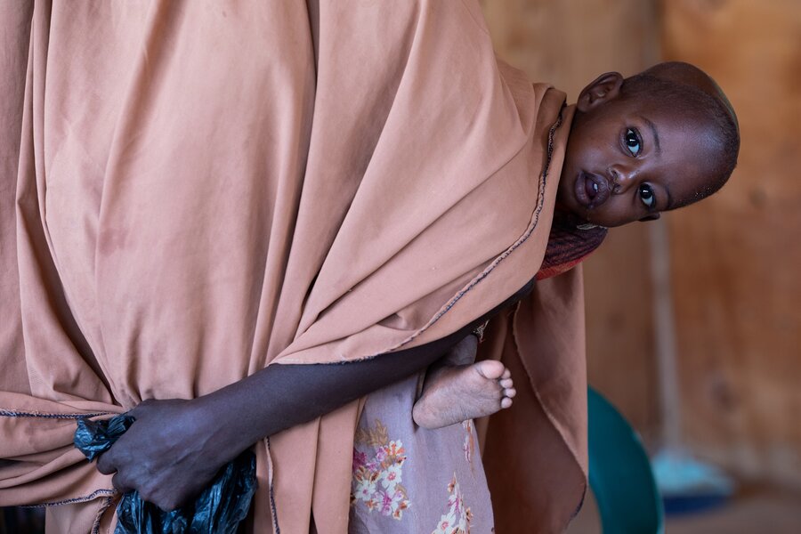 A baby peeks around its mothers pink sari