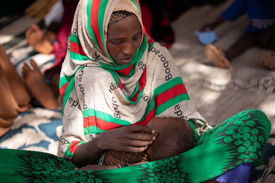 A mother holds her child in her arms and stares into their face