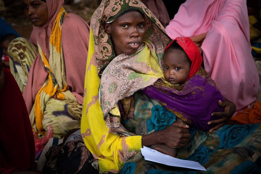 A Somali mother holds her baby while sitting in a group of women