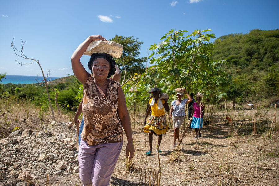 A woman carries a stone as part of a terracing project to control soil erosion.